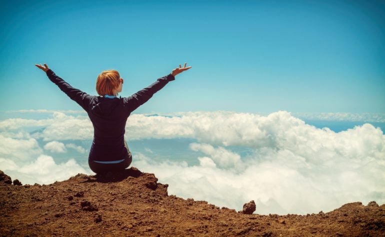 Woman sitting on mountain ledge